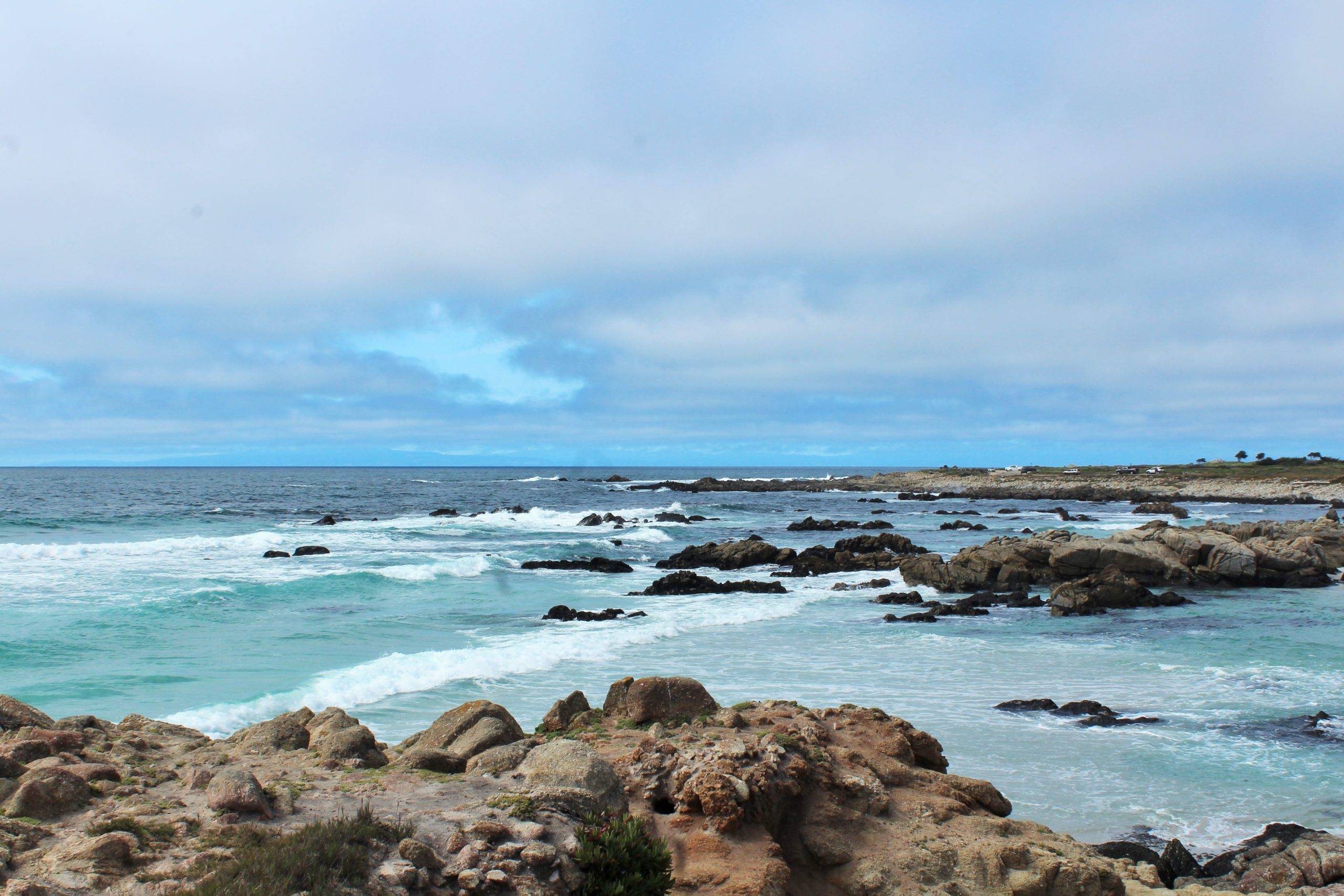 rocky shoreline with blue ocean and cloudy skies