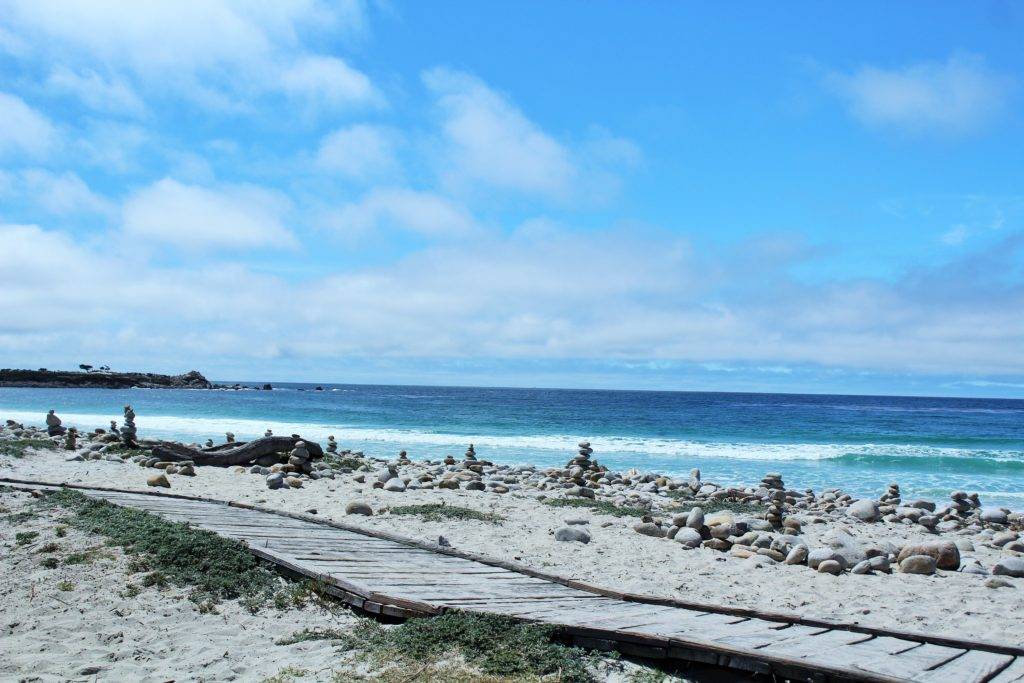 cairns on a white sand beach with blue water at 17-mile drive