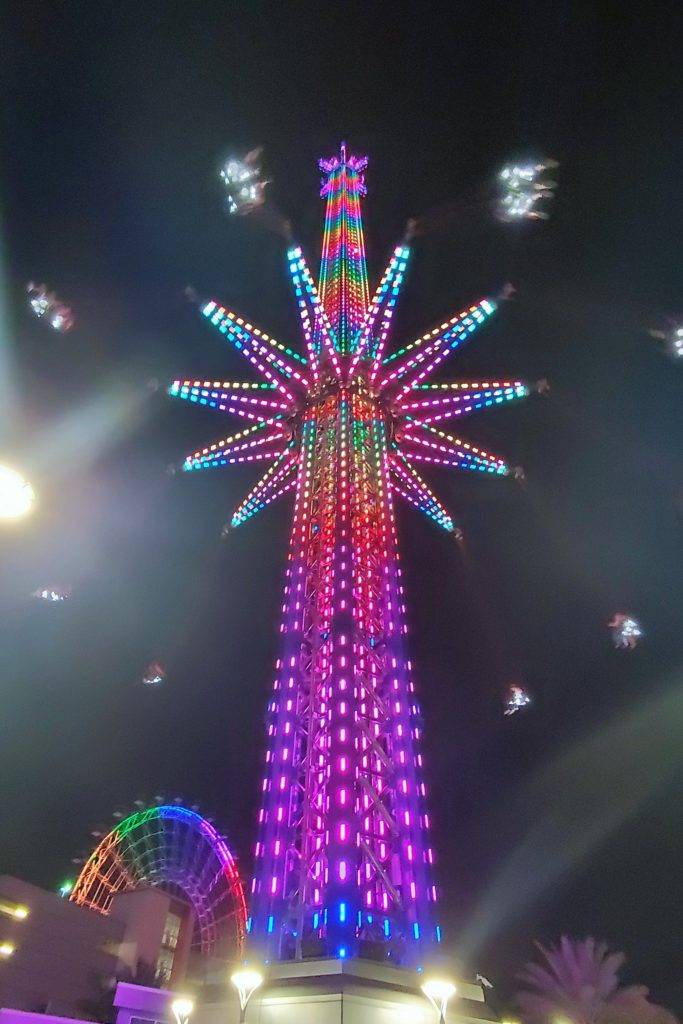 The StarFlyer at Icon Park: the world's tallest stand-alone swing ride lit up in neon colors at night. 
