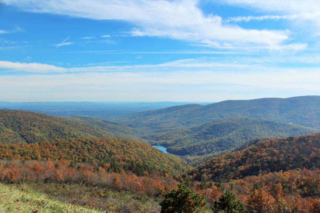 Sweeping valley with green and fall colors and a river winding through the center. Skyline Drive