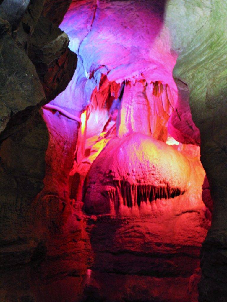 large flowstone rock formation colored with red and pink lights at Skyline caverns