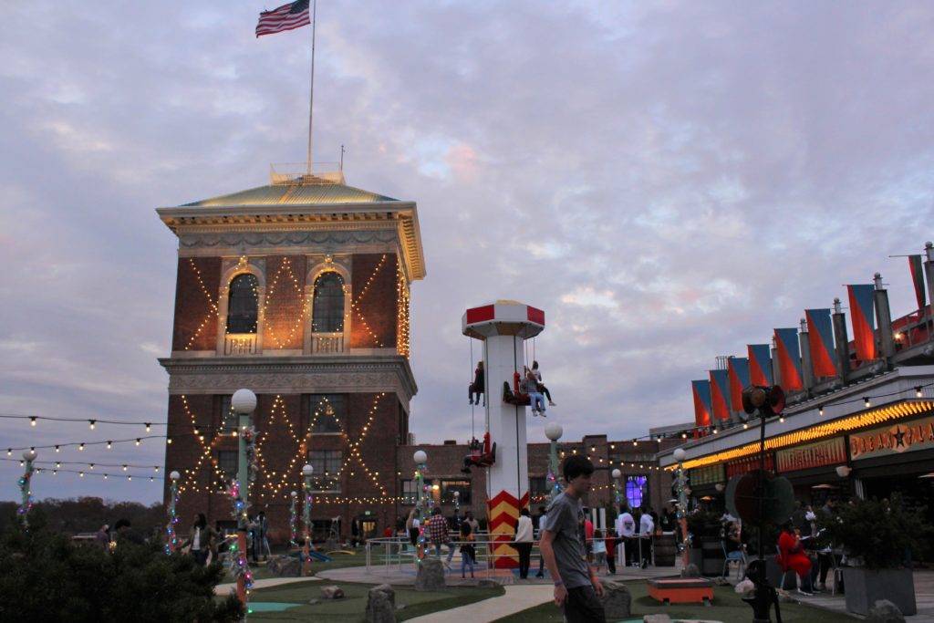 brick tower covered in lights in the background, amusement park in the foreground. the ROOF ponce city market