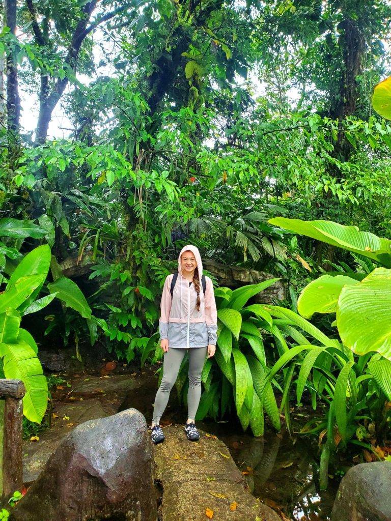 Girl standing in a lush costa rica rainforest with a rain jacket