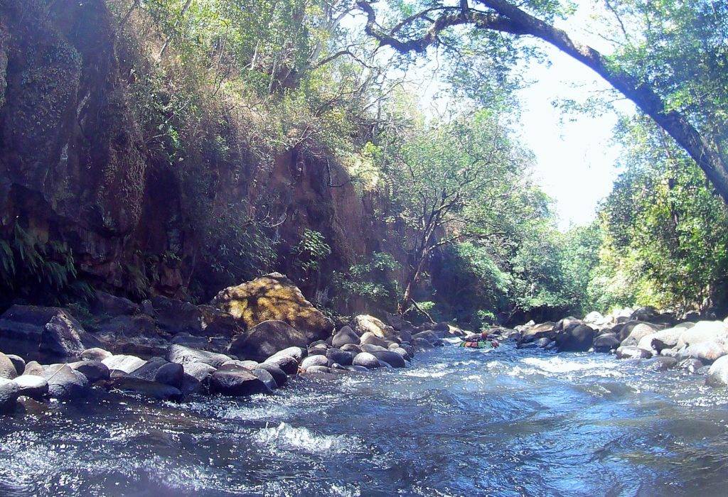 Rio Negro in Rincon de la Vieja. Churning river rapids with boulders and rocky wall on the left
