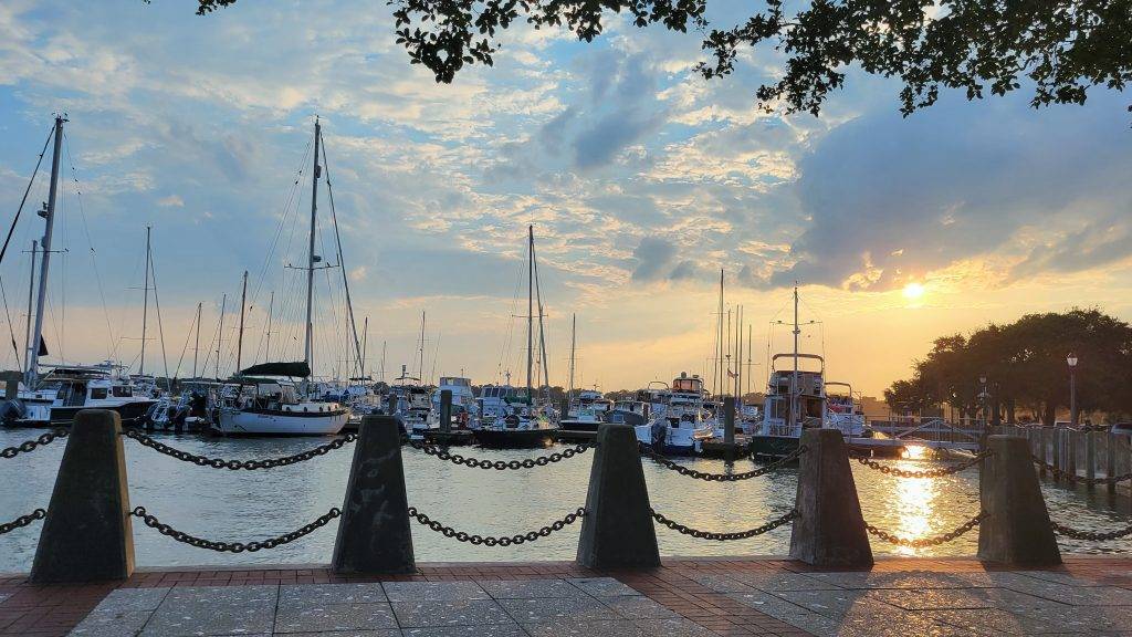 boats docked in a marina with the sun setting in the background. beaufort sc