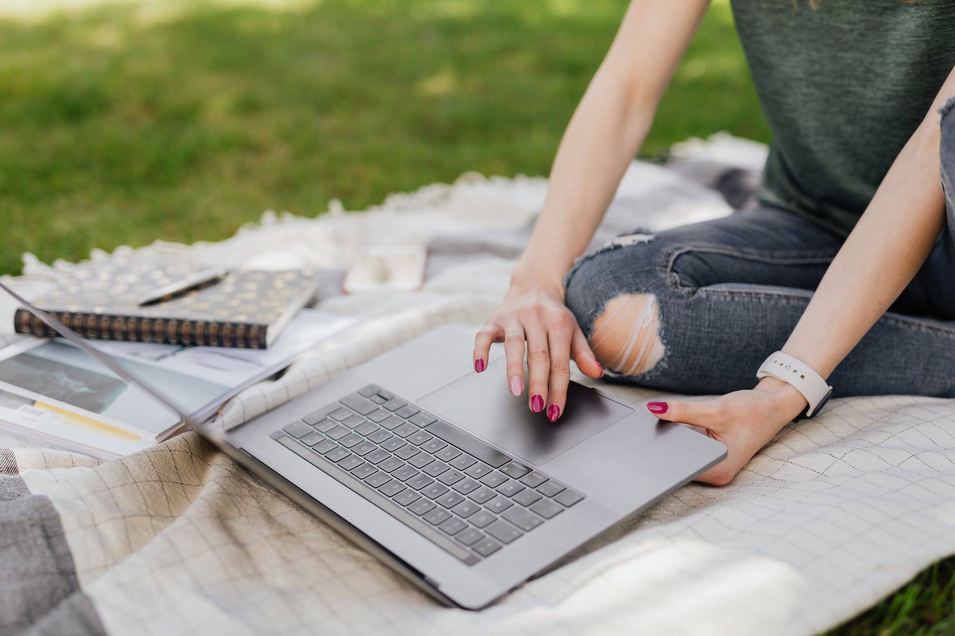 anonymous lady using laptop for studies in sunny park