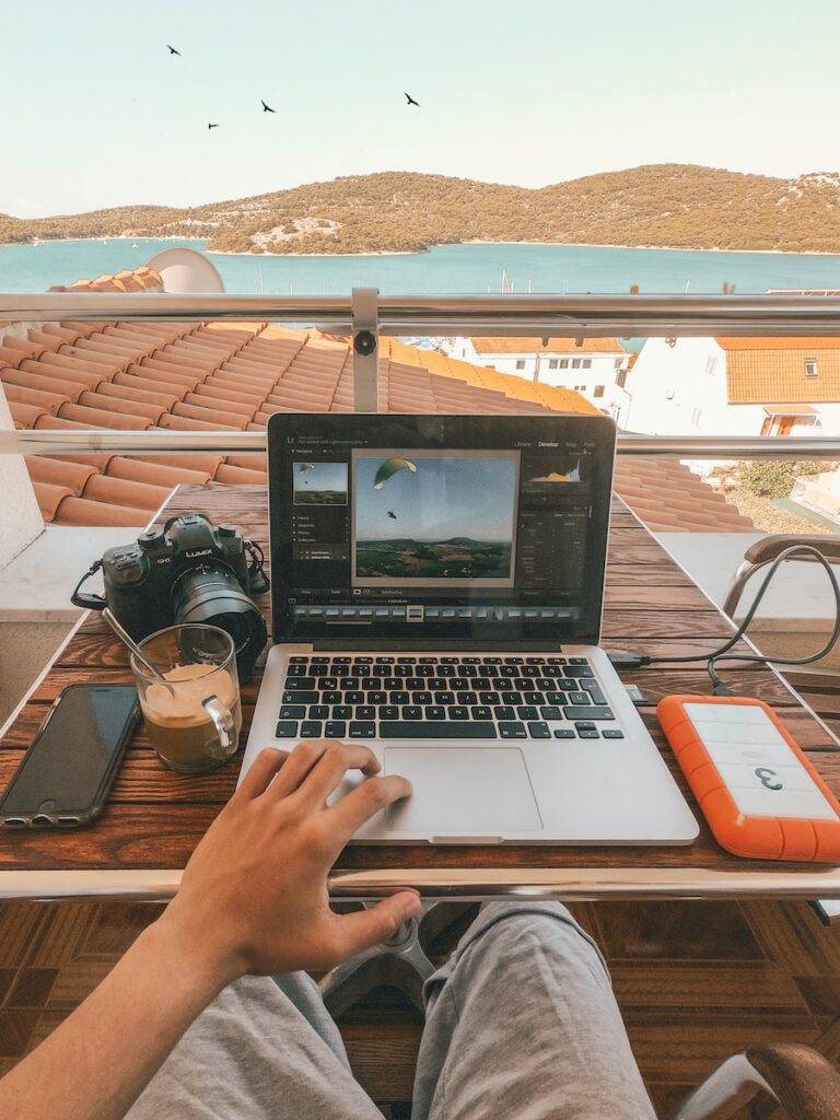 person holding MacBook Pro besides orange power bank work from hotels