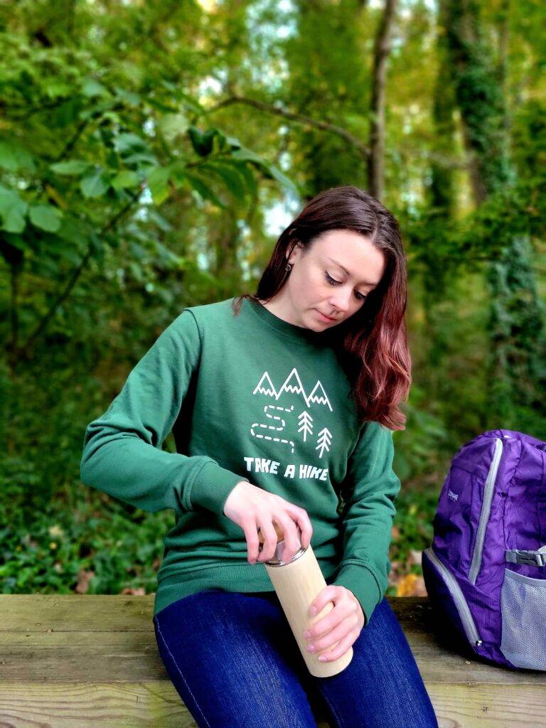 Girl in a forest with a waterbottle and a green hoodie