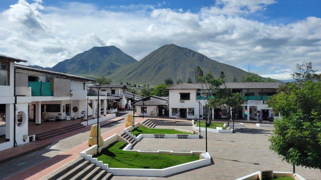 white buildings surrounding a courtyard with mountains in the background ecuador
