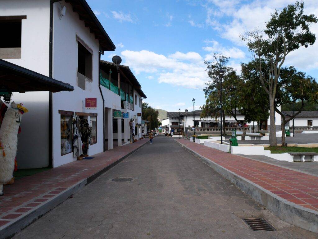 white shops lining a cobblestone street with brick sidewalks- middle of the world monument