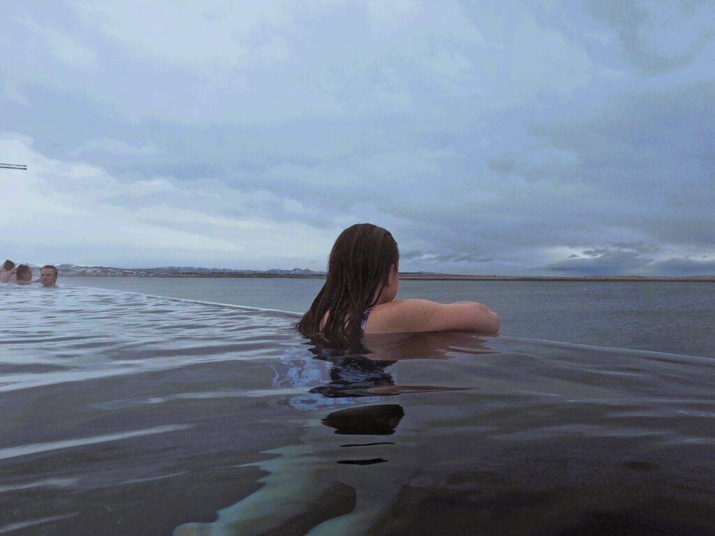 girl on edge of oceanfront infinity pool at Sky Lagoon, Iceland