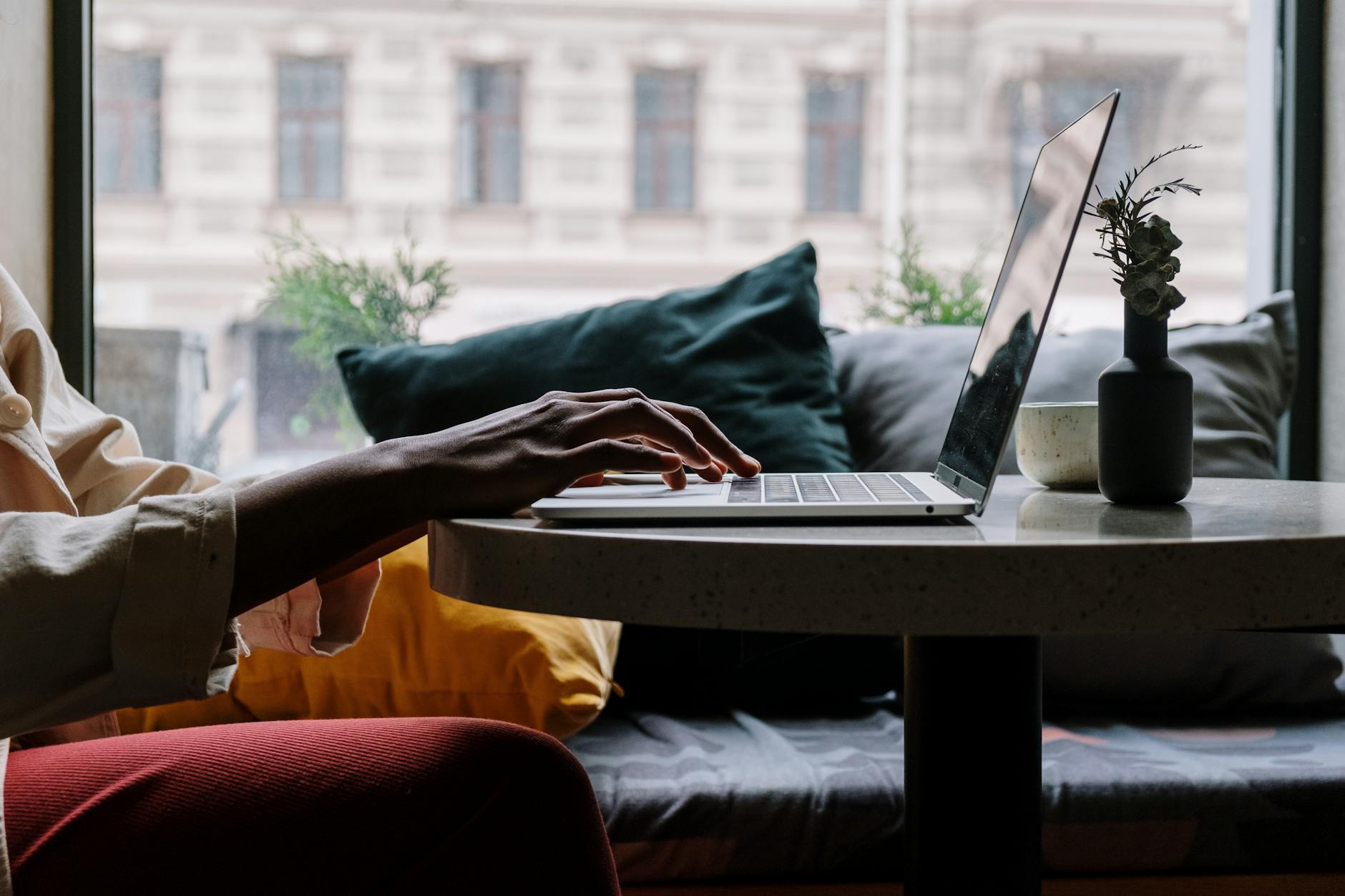 person in red pants sitting on couch using macbook digital nomads